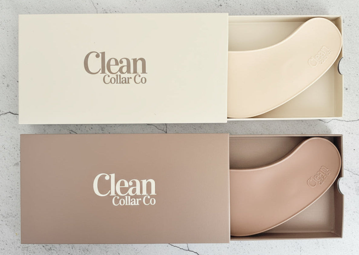Two clean collar co neckline protectors in boxes laying on a flat stone surface. 